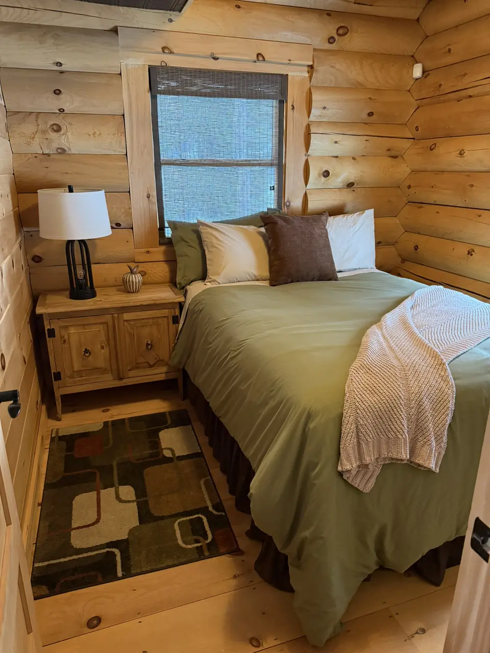 Main level bedroom with green bedding and nightstand lamps