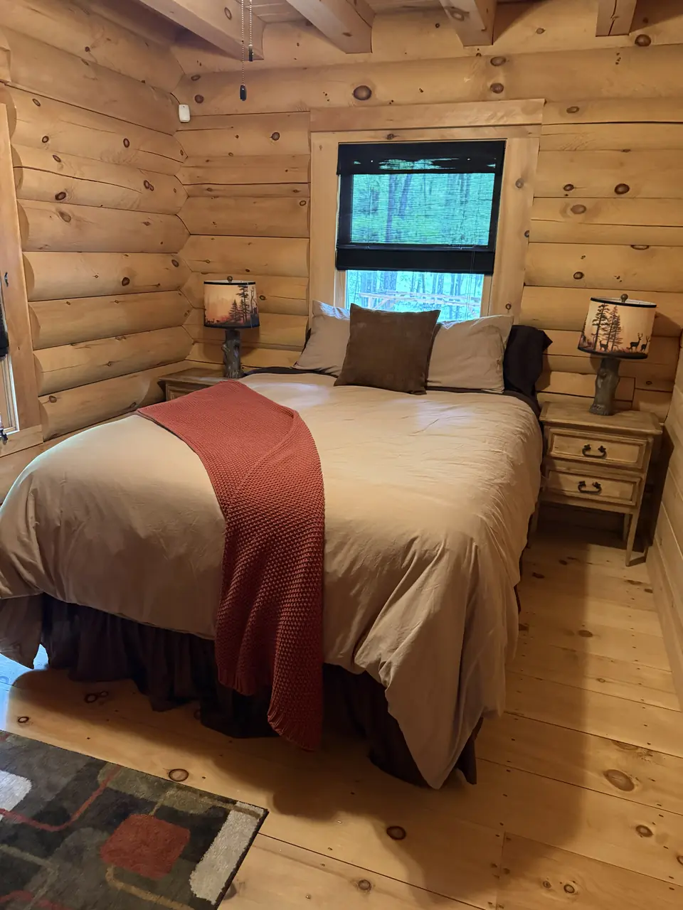 Main level bedroom with log walls and a window to the trees