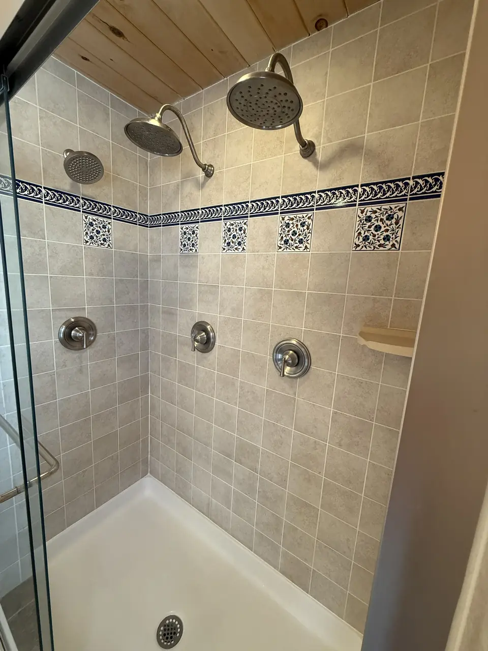 Tiled walk in shower with two shower heads in the primary bath