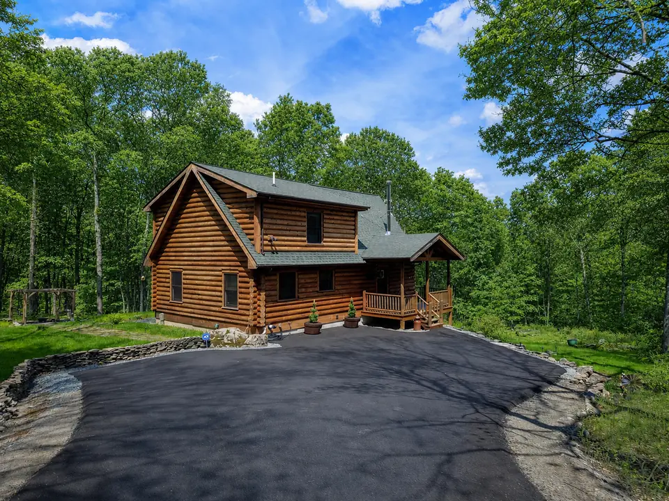 Front of the log cabin with the paved driveway and parking area