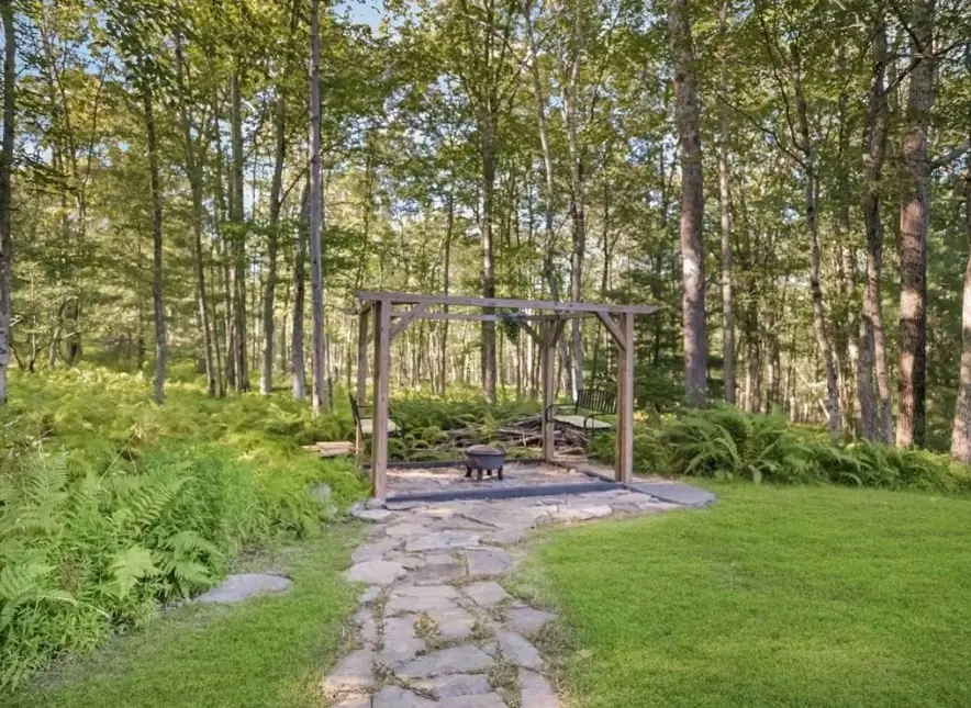Stone path through ferns leading to the pergola fire pit in the woods