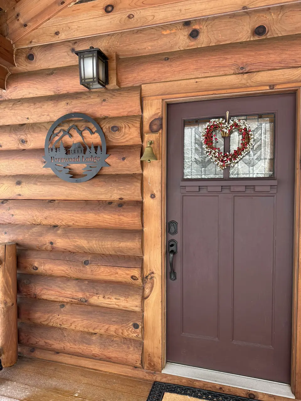 Front door of the log cabin with a wreath and lantern