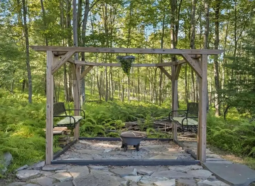 Timber pergola over the stone fire pit with swing seats and chairs