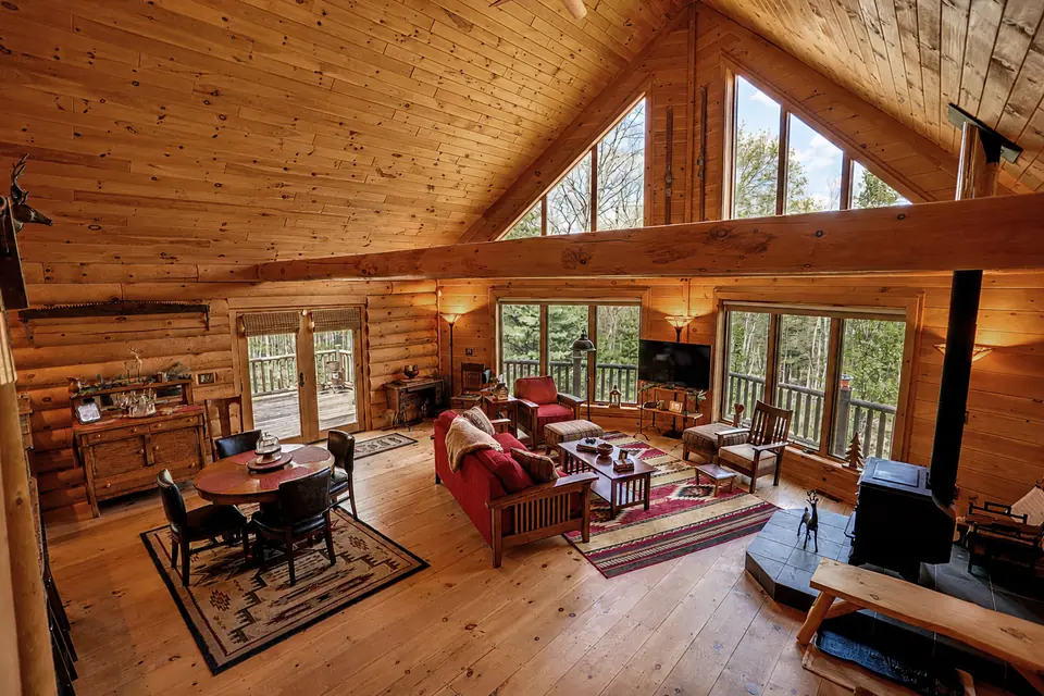 Dining table and living area beside tall windows in the log cabin great room