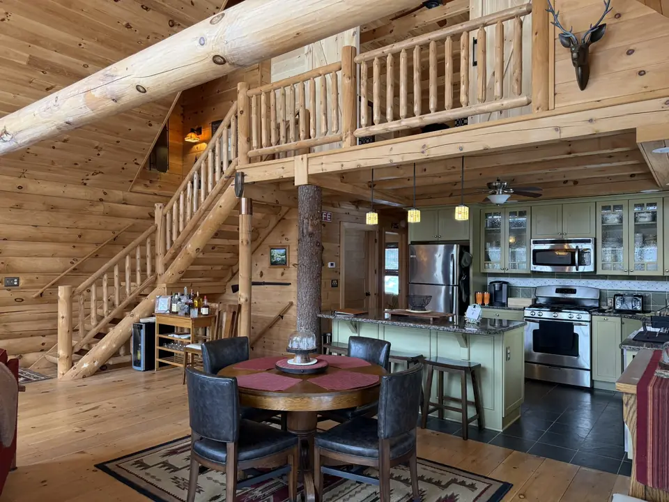 Kitchen with granite island, pendant lights, and the log staircase