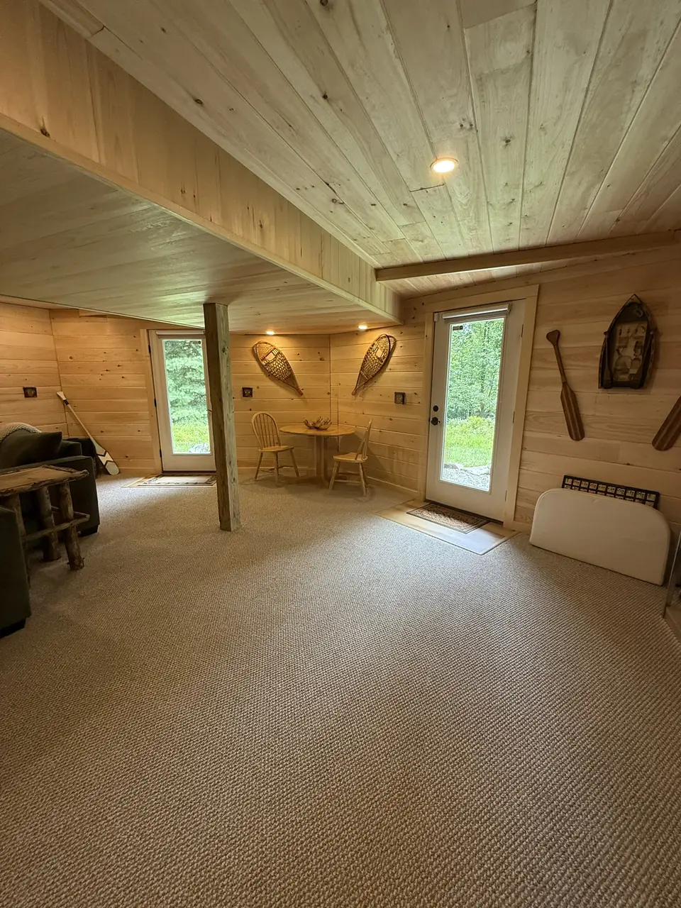 Lower level family room with carpet, pine ceiling, and a door to the yard