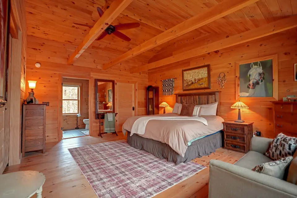 Primary suite with vaulted ceiling, ceiling fan, and sitting area