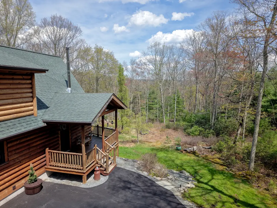 Side of the cabin and covered entry with the woods beyond in spring
